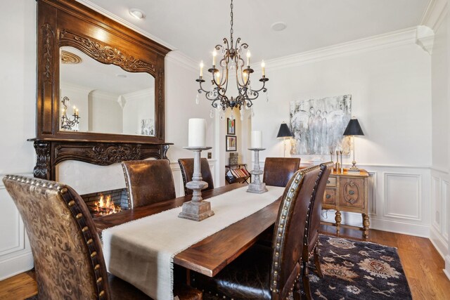 dining area featuring wainscoting, wood finished floors, a chandelier, and ornamental molding