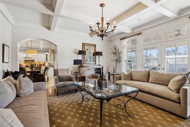 living area with arched walkways, an inviting chandelier, coffered ceiling, and crown molding