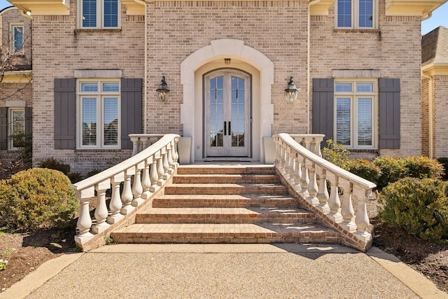 view of exterior entry featuring french doors and brick siding