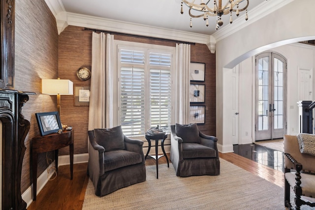 living area featuring baseboards, arched walkways, crown molding, and an inviting chandelier