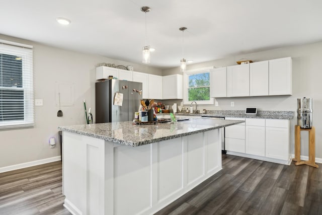 kitchen featuring a center island, dark wood-style floors, baseboards, freestanding refrigerator, and white cabinetry
