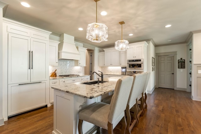 kitchen featuring a chandelier, appliances with stainless steel finishes, backsplash, a sink, and premium range hood
