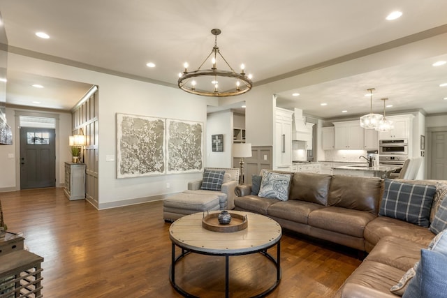 living room featuring baseboards, recessed lighting, a notable chandelier, and dark wood-style flooring