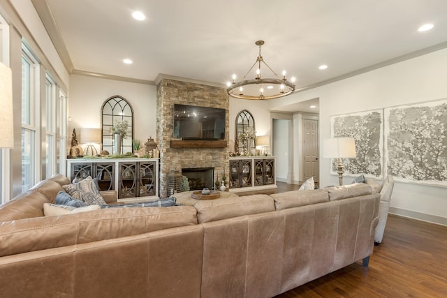 living room featuring recessed lighting, a notable chandelier, crown molding, a fireplace, and dark wood-type flooring