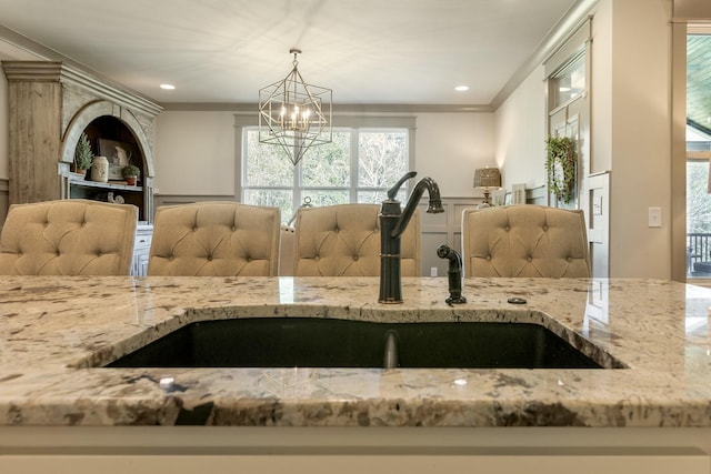room details featuring a sink, a chandelier, and light stone counters
