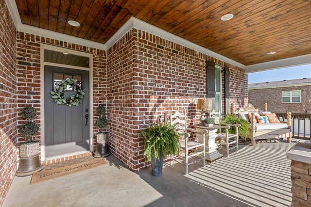 view of exterior entry with brick siding and covered porch