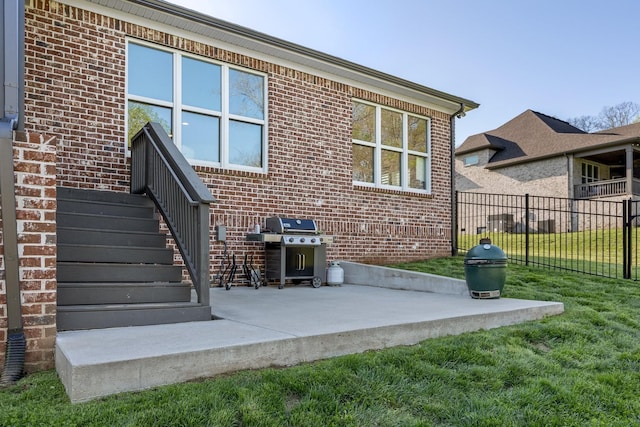 rear view of property with fence, a yard, a patio area, and brick siding