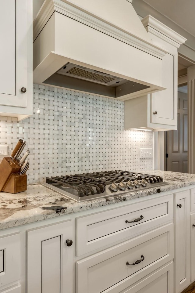 kitchen featuring backsplash, white cabinetry, stainless steel gas cooktop, and custom range hood