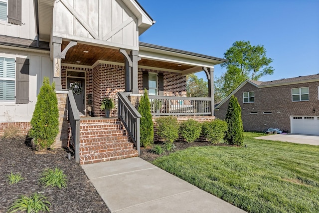 view of exterior entry with a lawn, brick siding, a porch, and board and batten siding