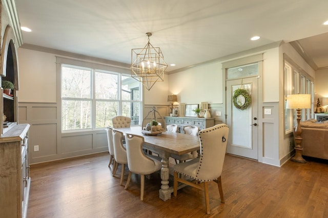 dining room featuring wainscoting, wood finished floors, a chandelier, and a decorative wall