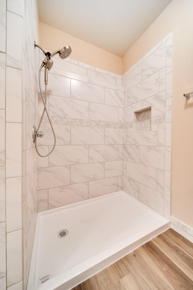 bathroom with a tile shower and wood finished floors