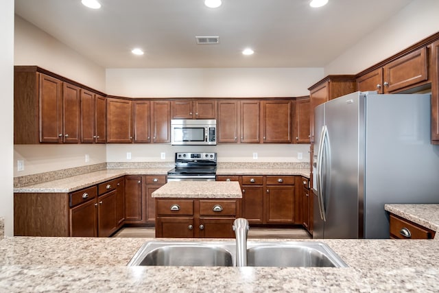 kitchen with appliances with stainless steel finishes, a sink, and light countertops