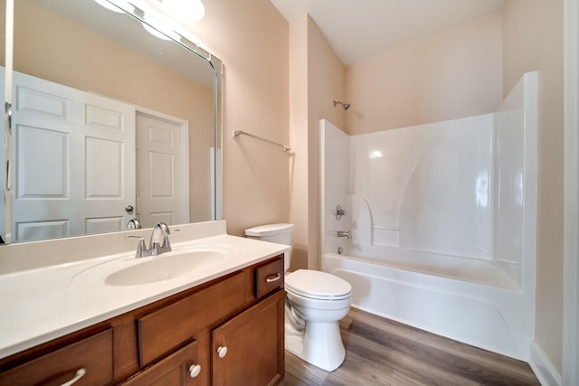 bathroom featuring wood finished floors, toilet, vanity, and shower / washtub combination