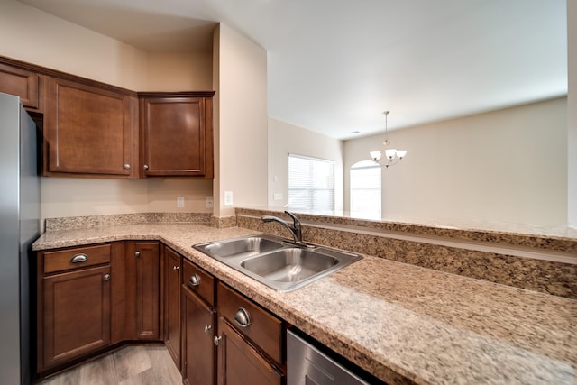 kitchen featuring a chandelier, a sink, light countertops, and freestanding refrigerator