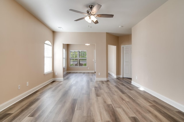empty room featuring ceiling fan, baseboards, wood finished floors, and visible vents