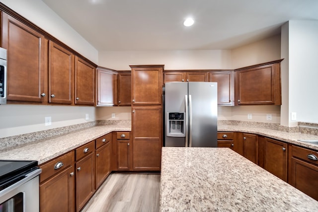 kitchen with light stone counters, appliances with stainless steel finishes, light wood-style floors, and recessed lighting