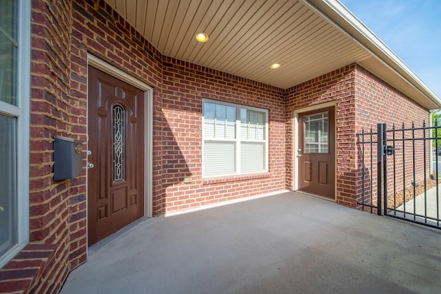 doorway to property featuring fence, a patio area, brick siding, and a gate