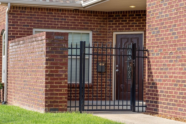 view of exterior entry featuring brick siding, fence, and a gate