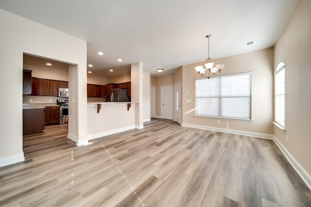 unfurnished living room featuring recessed lighting, visible vents, light wood-type flooring, baseboards, and a chandelier