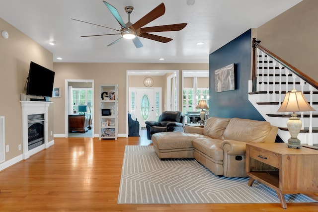 living area with recessed lighting, wood finished floors, a glass covered fireplace, baseboards, and a ceiling fan