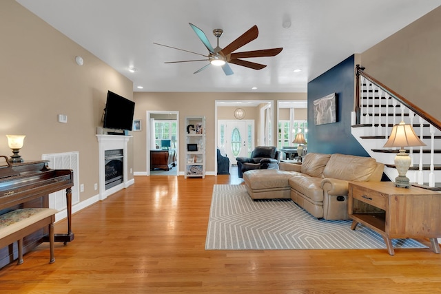 living area with light wood finished floors, a fireplace, ceiling fan, visible vents, and baseboards