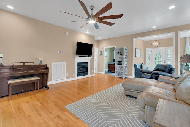 living area with a ceiling fan, visible vents, baseboards, and light wood-type flooring