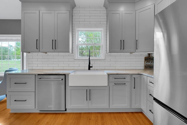 kitchen featuring backsplash, light wood finished floors, a sink, and appliances with stainless steel finishes