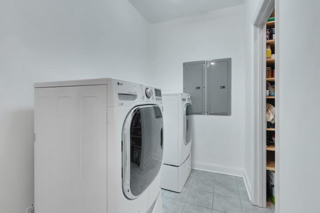 clothes washing area featuring light tile patterned floors, separate washer and dryer, electric panel, laundry area, and baseboards