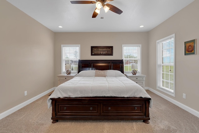 bedroom featuring multiple windows, ceiling fan, light carpet, and baseboards