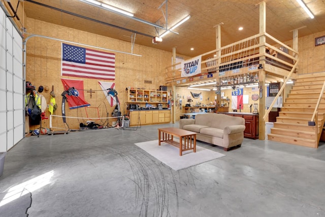 interior space with a high ceiling, a garage, stairway, concrete floors, and a workshop area