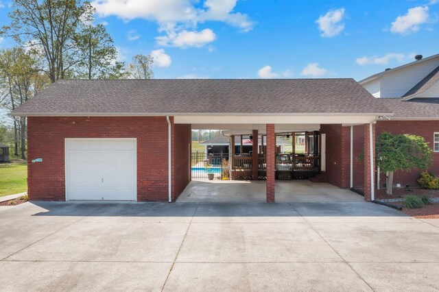 view of front of home featuring brick siding, fence, concrete driveway, and roof with shingles