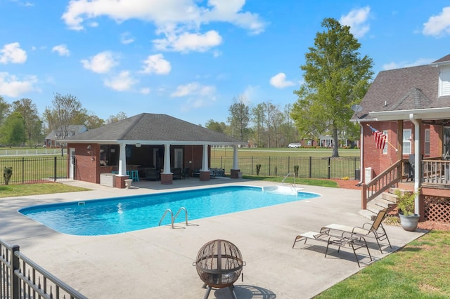 view of swimming pool featuring a patio, a fenced in pool, a fire pit, and fence