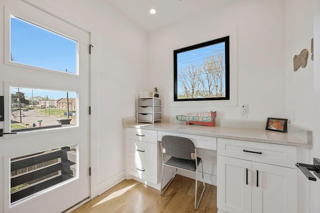 office space with light wood finished floors, built in desk, recessed lighting, and baseboards