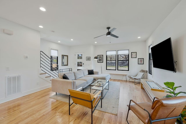 living room with stairs, plenty of natural light, ceiling fan, light wood-style floors, and recessed lighting