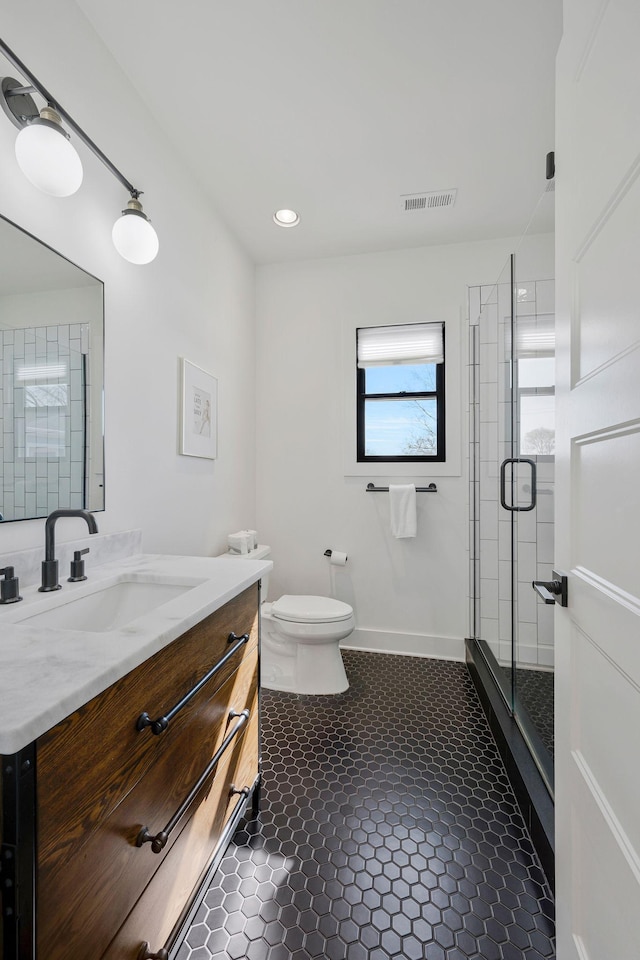 bathroom featuring a shower stall, toilet, vanity, and tile patterned flooring