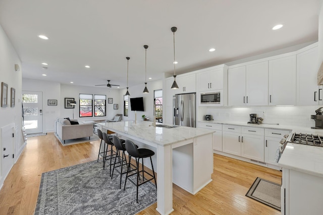 kitchen featuring stainless steel appliances, open floor plan, a center island, tasteful backsplash, and a ceiling fan