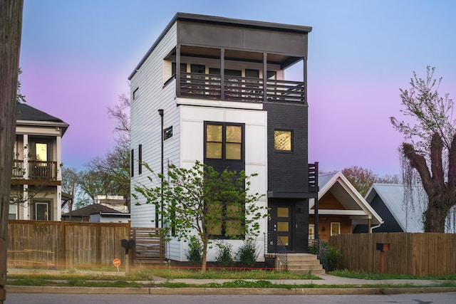 modern home featuring a balcony and fence