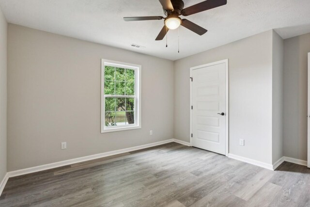 1212 Hollis Ln, Lafayette, TN 37083 - empty room with wood finished floors, visible vents, a ceiling fan, and baseboards