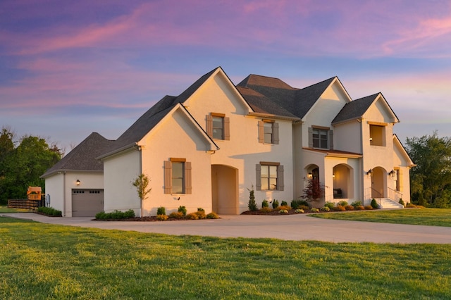 view of front facade with driveway, stucco siding, a front lawn, and an attached garage