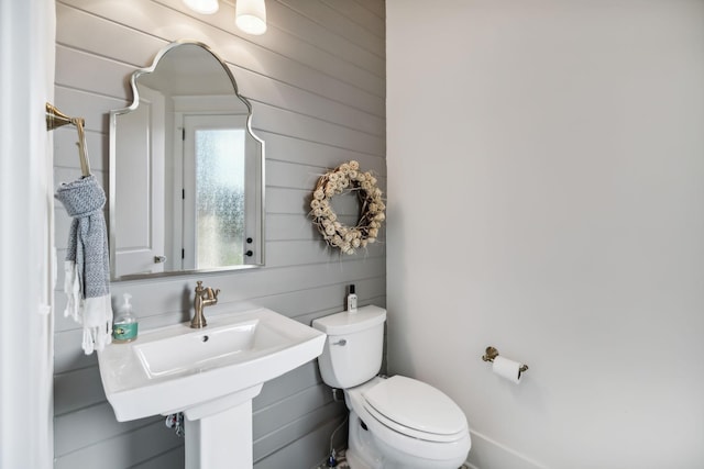 half bathroom with toilet and wooden walls