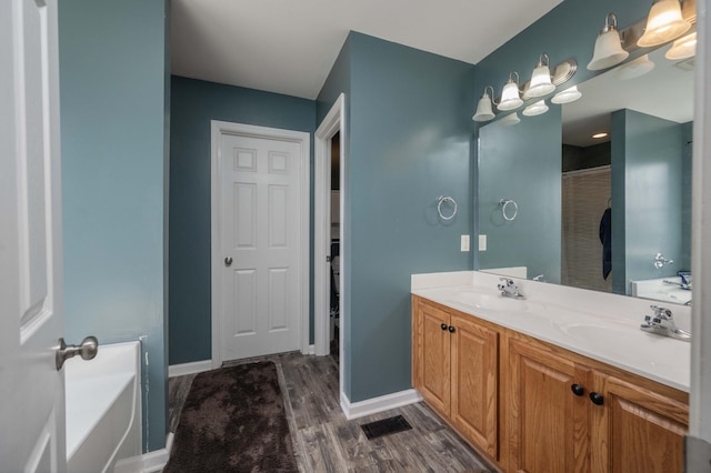 bathroom featuring visible vents, wood finished floors, a sink, and double vanity