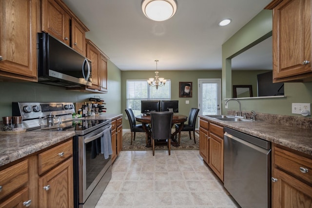kitchen featuring a sink, a notable chandelier, pendant lighting, brown cabinets, and appliances with stainless steel finishes