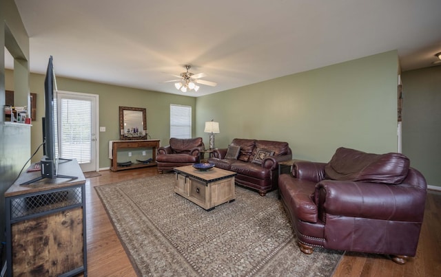living room with baseboards, wood finished floors, and ceiling fan