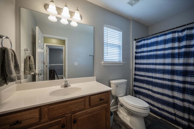 bathroom with wood finished floors, visible vents, toilet, vanity, and baseboards