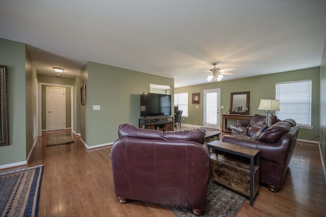 living room with wood finished floors, a ceiling fan, and baseboards