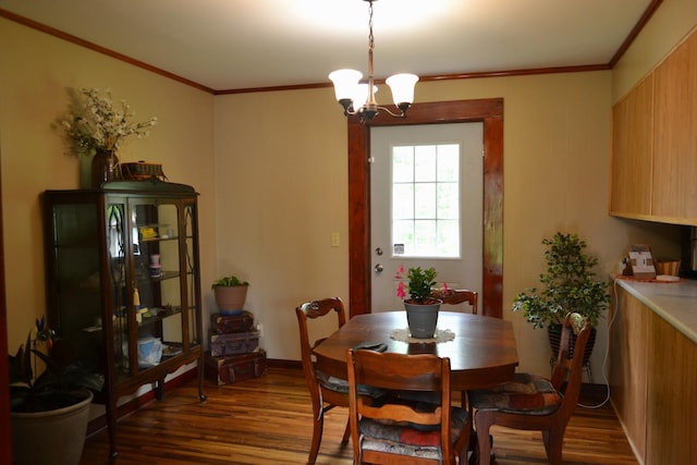 dining space featuring dark wood-type flooring, a chandelier, and ornamental molding