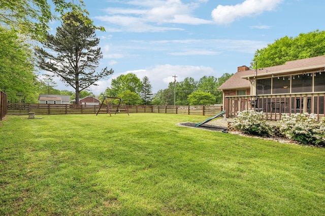 view of yard featuring a sunroom, a fenced backyard, and a playground