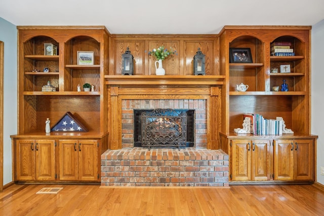 living area featuring light wood-type flooring, baseboards, visible vents, and a fireplace