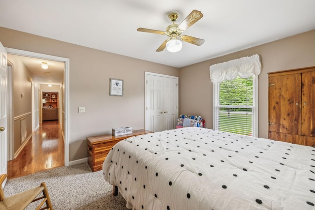 bedroom featuring light carpet, a ceiling fan, baseboards, and a closet
