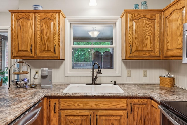 kitchen with brown cabinetry, dishwasher, and a sink